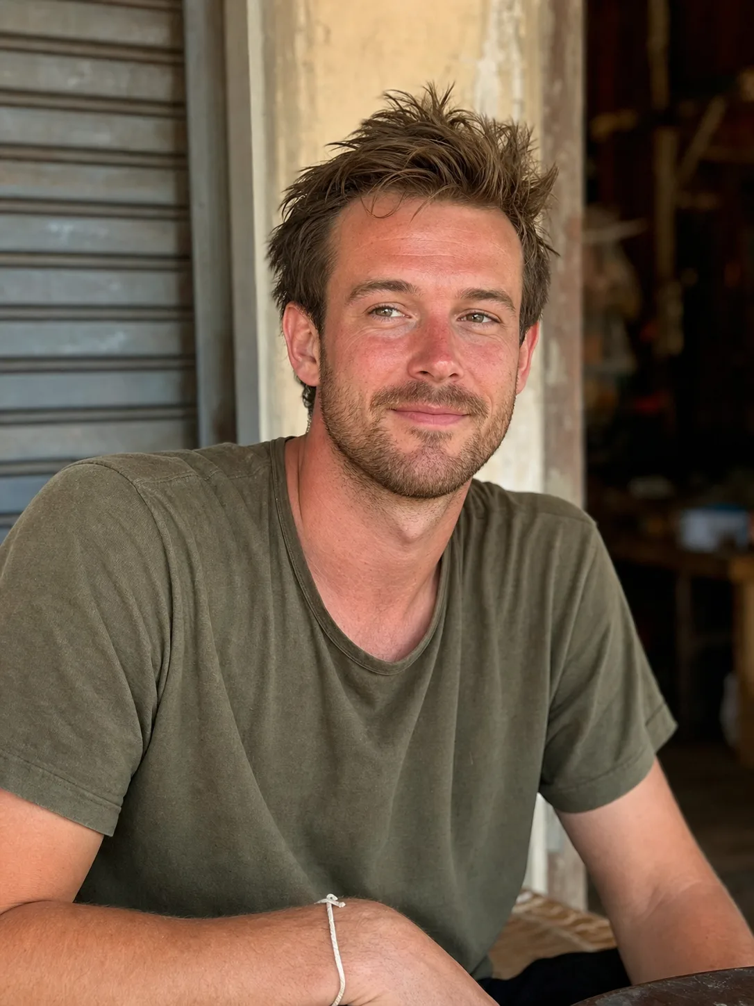Alex, sunburnt and half-smiling, half-length portrait on the trip, string on his wrist